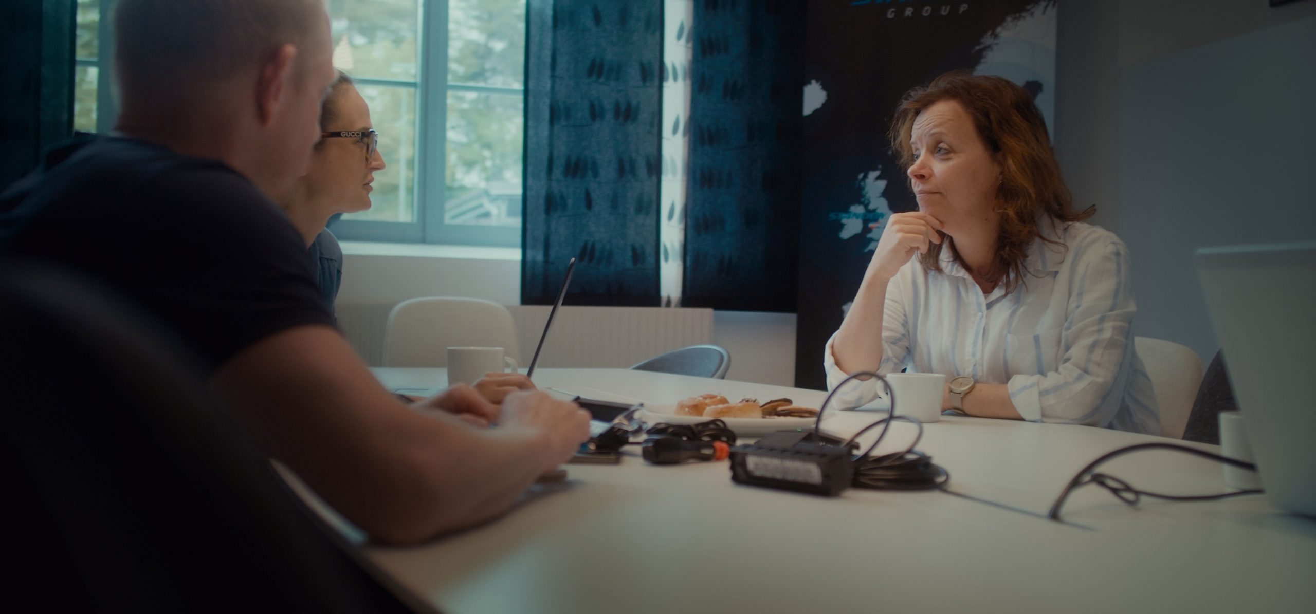 Hero Image 3 Person Conversation Sitting Around Table Holding Discussion with Refreshments and Equipment on Table