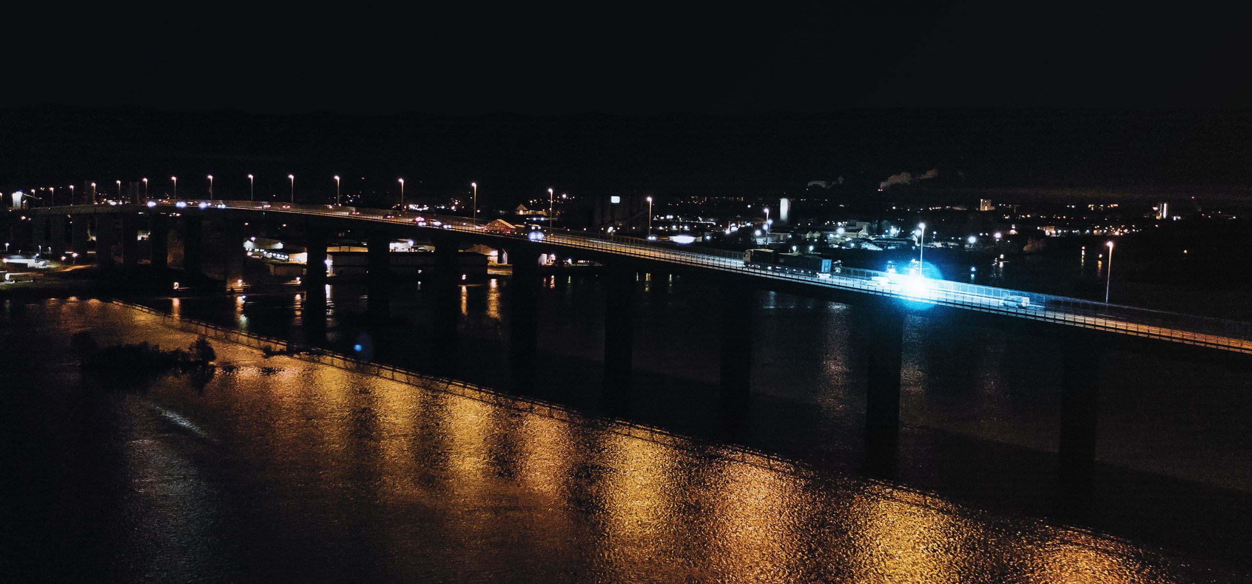 Hero Image Bridge at Night Across Water with Emergency Vehicle with Blue Lights Crossing