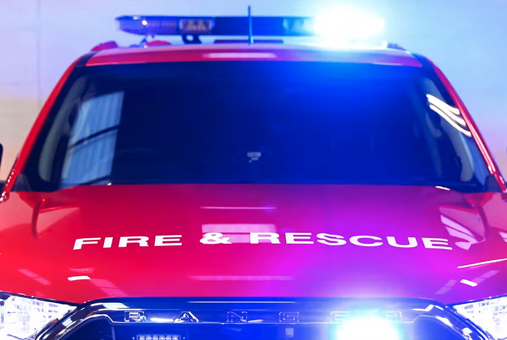 Front view of fire response vehicle with fire and rescue livery, lit lightbar and grille lights