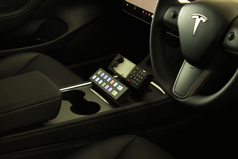 Closely cropped image of a Tesla centre console with Standby UK Handset under emergency radio